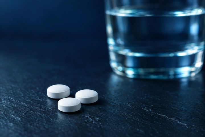 White oral tablets beside a glass of water
